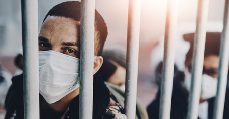 Mask, portrait and virus with man in cage as isolation for outbreak or pandemic in urban town. Face,...
