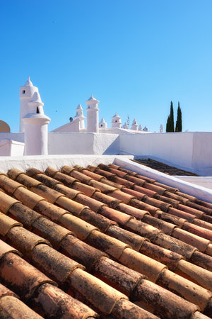 Building, rooftop and tiles with chimney, architecture and blue sky for ventilation with aesthetic. Culture, heritage and terracotta with sustainability, insulation or eco friendly clay roof in Spainの写真素材