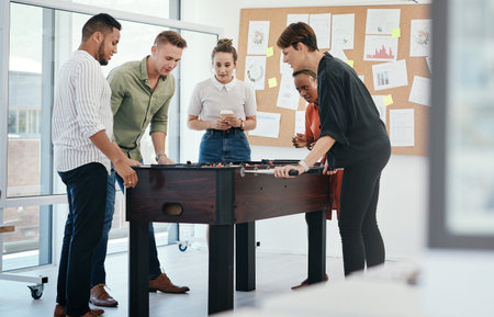 Happy people, foosball or playing with game for team building or bonding together at office. Young, group or employees enjoying fun competition, board challenge or football entertainment at workplaceの写真素材