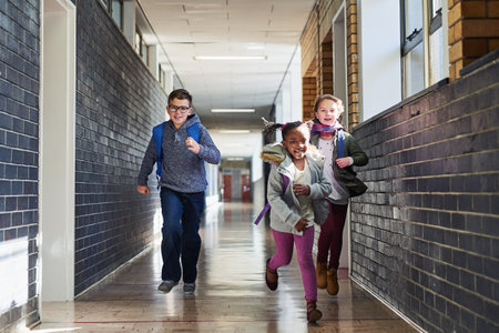Education, school kids and students running in corridor for recess, learning break and energy with backpack. Learners, friends and race in hallway for fun activity, challenge and child developmentの写真素材