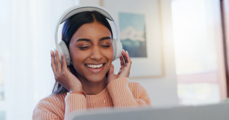 Home, headphones and woman with laptop, listening to music and happiness in living room. Apartment, person and girl with computer, headset and sound with song, radio, podcast for motivation and smileの写真素材