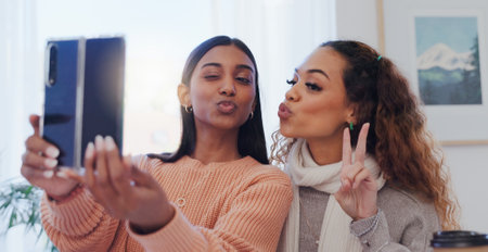 Selfie, friends and women with peace sign, home and bonding in living room, content creator and post. House, photography and memory for influencer, pout and profile picture in lounge and togetherの写真素材