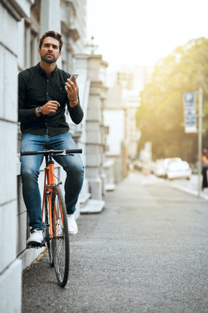 Bike, phone and confused with man in city for communication, social media or connection. Networking, newsletter and location app with person and mobile in downtown for travel, digital or internetの写真素材