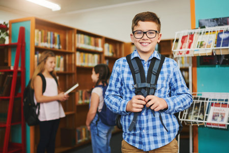Library, backpack and portrait of boy student in school with glasses for vision or learning. Happy, face and young child with growth, development and education at academy for knowledge or study.の写真素材