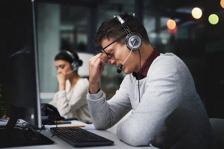 Man, call center and headache at night in office with stress, exhausted and pain by computer for...