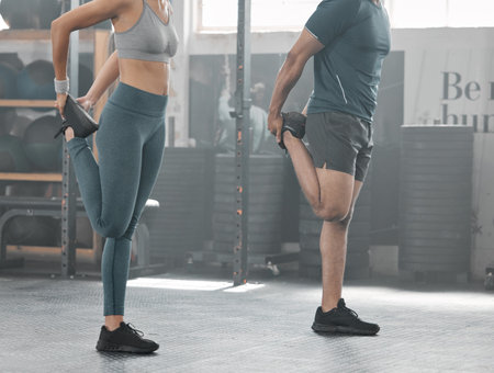 Fit, active and strong couple doing warmup and stretching before a workout at the gym. Sporty...