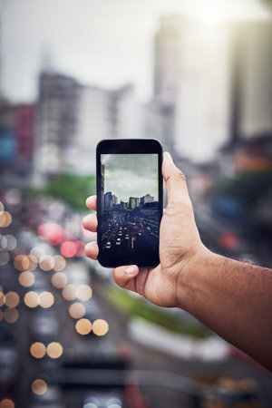Cityscape, hand and person with phone for picture, photography and digital memory on vacation travel. Bokeh, influencer or photographer with mobile app for camera capture, adventure and social mediaの写真素材