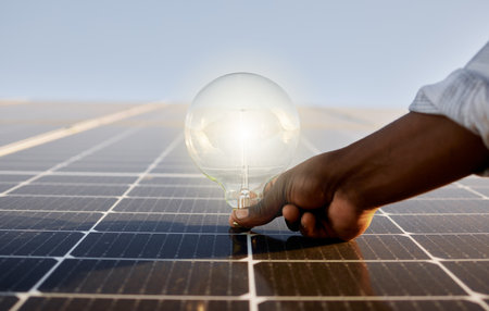 Light bulb, solar panel and hand with renewable energy, sustainability and clean power. Person, alternative generator and carbon neutral technology in conservation, environment and green electricityの写真素材