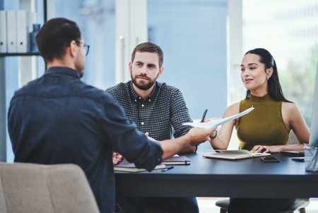 Creative, business people and group discussion with documents in meeting for design or target audience. Team, project manager and planning with paperwork for campaign, solution or strategy in startupの写真素材