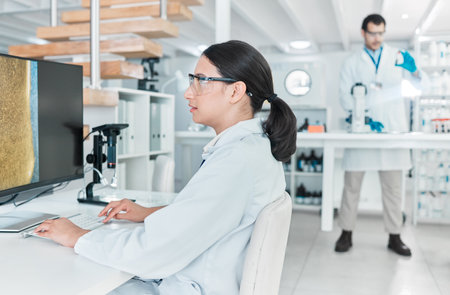 Woman scientist, desktop and medical research in science lab for chemistry experiment in healthcare. Female person, technology and results in pharmaceutical test, analysis or mpox vaccine in hospitalの写真素材