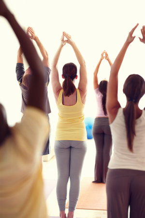 Yoga, stretching and people in class for wellness, health and workout for mobility with trainer. Studio, gym and men and women for exercise, training and fitness for pilates, balance and flexibilityの写真素材