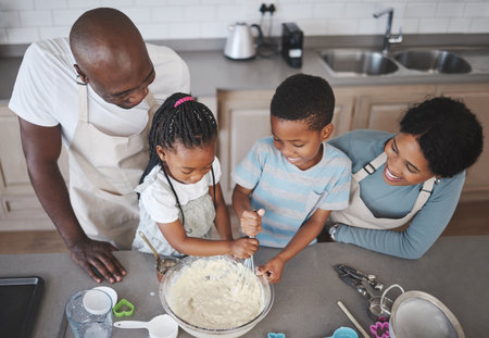 Whisk, bowl and black family baking in kitchen for bonding, learning and skill development in home. Mixing, ingredients and African parents teaching children to cook for growth and fun at house.の写真素材