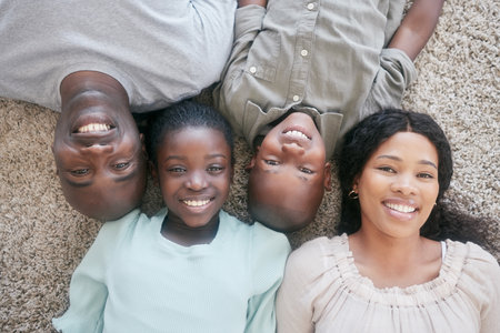 Black family, happy and portrait on floor in home with support, bonding and relationship with love, care or security. People, parents or kids with smile on carpet with top view, relax or fun togetherの写真素材