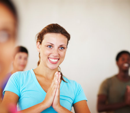 Happy woman, yoga class and meditation with namaste for spiritual wellness, awareness or zen at dojo. Young, female person or group with smile for pilates, workout or exercise together in studioの写真素材