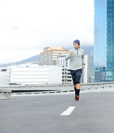 Fitness, running and man in city for cardio jog, race or training for healthy body. Sports, exercise and runner on street outdoor for wellness, energy or workout on bridge in winter with mockup spaceの写真素材