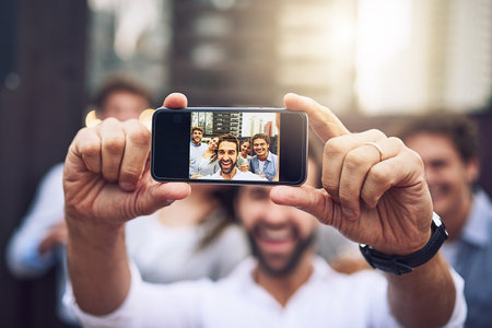 Business people, selfie and screen with smile, friends and after work with social media and post. Profile picture, technology and happy staff excited for the weekend with internet and app with teamの写真素材