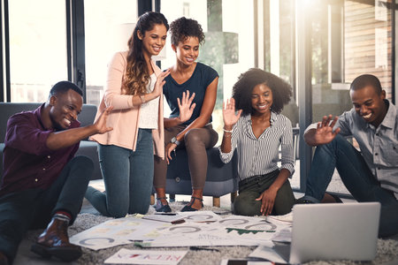 Business people, video call and office floor with laptop and content creation planning and talk. Online presentation, greeting and creative agency with SEO update strategy with diversity and notesの写真素材