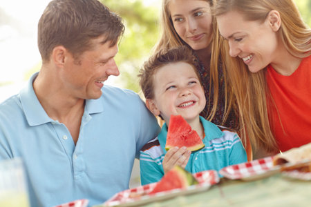 Family, happy and excited in nature for picnic, fun activity and watermelon for refreshing snack. Parents, children and favorite fruit in park for relationship development on vacation in Australiaの写真素材