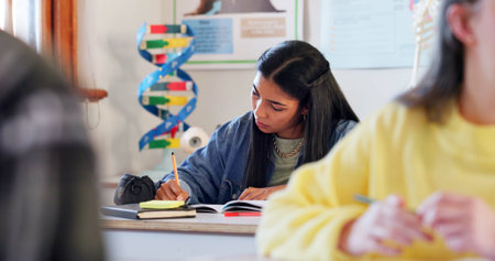 Writing, study and student in classroom for learning chemistry with notes for exam, test or project. Education, teenager and girl in lesson with books for science at school academy with scholarship.の写真素材