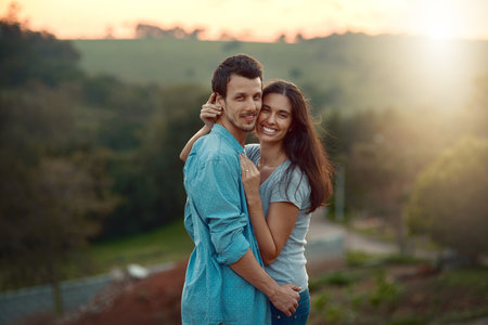 Love, portrait and hug with couple in nature for support, bonding and honeymoon vacation. Relax, care and adventure with people and smile on date for travel holiday, sunset and romance togetherの写真素材