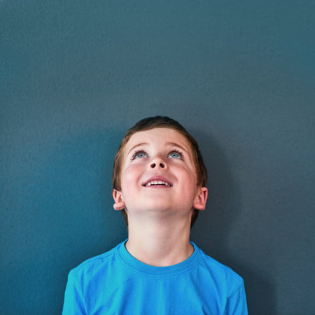 Excited, happy and child looking up in studio for omg news, opinion and feedback on blue background....