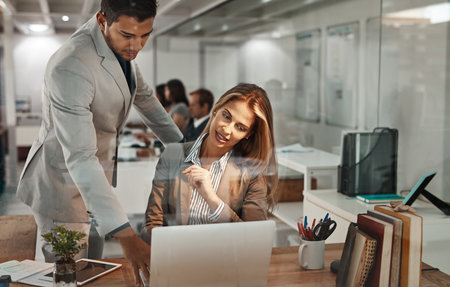 Business woman, laptop and mentor with collaboration, coaching and training for advice in office. Manager, help and employee with computer, partnership and support for project planning in nightの写真素材