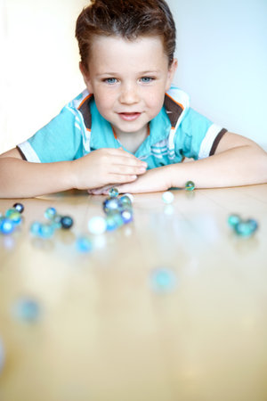 Floor, boy and serious with playing marbles on portrait for fun on school break at home in Scotland. Male person, kid and concentration at apartment for games, child growth and brain developmentの写真素材