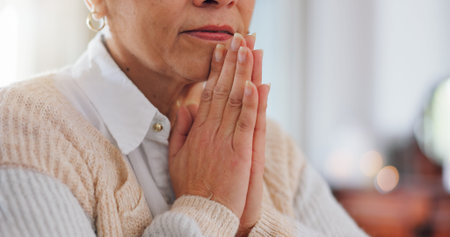 Religion, hands and praying with senior woman in home for religious healing, mercy or guidance in...