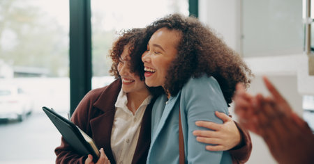 Business, women and happy on hug at office for career opportunity, job promotion and success. People, employee and excited or smile with applause for teamwork, collaboration and solidarity on projectの写真素材