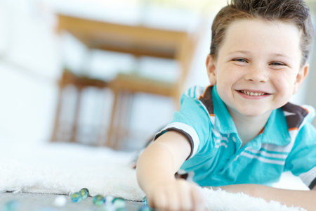 Happy child, portrait and kid play with marbles on floor for game, relax and fun in home. Smile,...