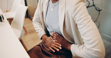 Professional, woman and hands with stomach pain in office for menstrual cramps, constipation and digestion problem. Employee, abdomen and endometriosis emergency with uncomfortable ache and crisisの写真素材