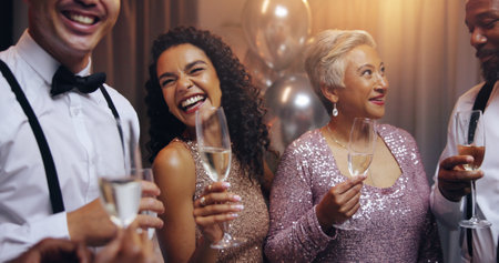 Business people, group and happy with champagne at party, conversation and celebration for new year. Women, men and smile with friends, diversity and glass for alcohol, drinks and gala event at nightの写真素材