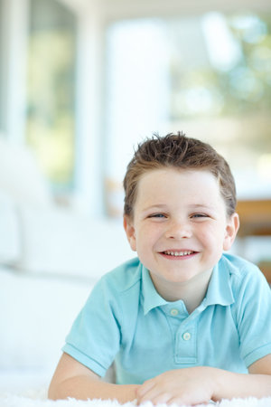 Boy, happy child and lying in home portrait, morning confidence and chilling on floor of living...