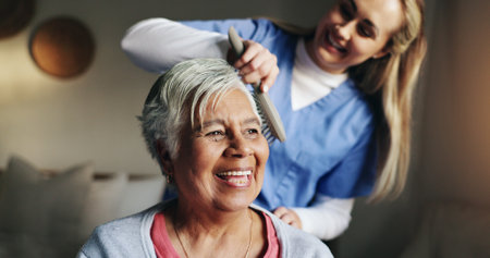 Brush, help and nurse with patient for hair in retirement home at healthcare consultation. Happy, medical checkup and caregiver assisting elderly woman with hairstyle in morning at nursing facility.の写真素材