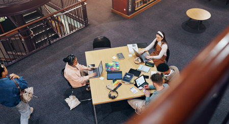 Above, laptop and studying of group, library and browsing of web, education and friends with...