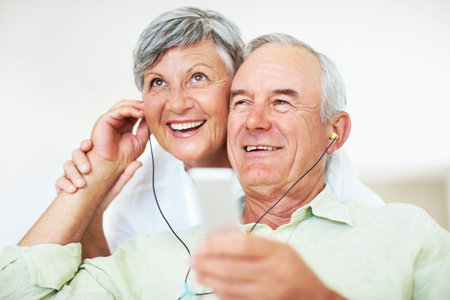 Sofa, senior couple and happy with earphones for music, hearing and connection for bonding together....