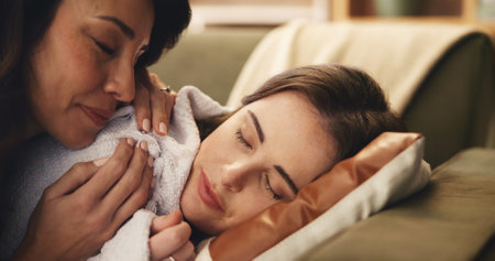 Sofa, mother and daughter with blanket for sleeping, comfort and parent for security in living room. Home, mature mom and adult child on couch for rest, bonding together or mama for support in loungeの写真素材