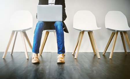 Row, chair and person with laptop, waiting room and professional in business, recruitment and online. Appointment, applicant and typing of resume, job interview and process of hiring and websiteの写真素材