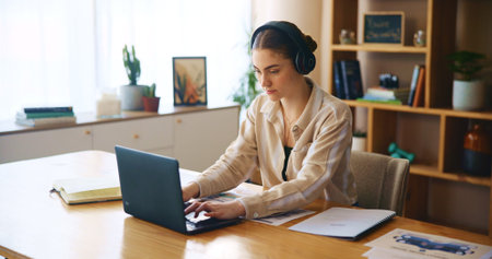 Remote work from home, laptop and woman with headphones, listening to music and typing. Person,...