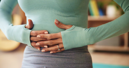 Living room, woman and hands with stomach pain for diarrhea, menstruation and constipation of virus. Female person, home and abdomen with tummy ache for ibs cramps, gastro problem and digestion issueの写真素材