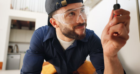 Plumber, man and tools for pipe in kitchen with home maintenance and fixing leak by sink with glasses. Plumbing contractor, handyman and screwdriver for filter system installation for small businessの写真素材