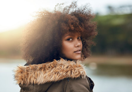 Girl, outdoor and portrait on holiday by lake, afro and travel for vacation, nature and getaway in sunshine. Woman, person and curly hair with view of river, water and morning on adventure in Brazilの写真素材