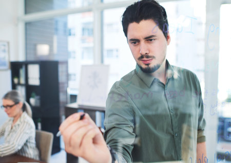 Business, man or writing on glass wall in office for brainstorming ideas, planning schedule or...