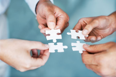 Hands of business people, challenge and teamwork with puzzle for problem solving, growth or...