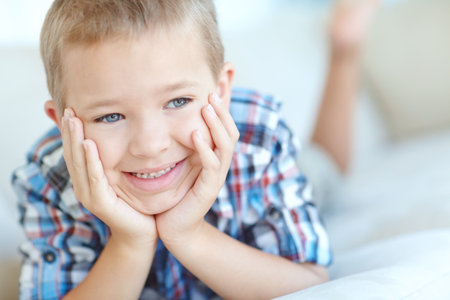 Thinking, smile and child in home, cute and relax in living room, adorable and mindset in weekend. House, contemplating and boy with ideas, rest and daydreaming in lounge, chilling and happy kidの写真素材
