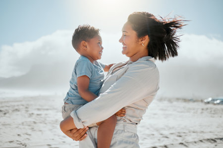 Love, smile and mother with son at beach for travel destination, summer and vacation. Relax, tropical and adventure with woman and holding child for family holiday, bonding and happiness togetherの写真素材