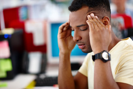 Business, headache and black man in office, pain and sick with burnout, overworked and stress. African person, creative agency or employee with migraine, fatigue or tired with deadline or health riskの写真素材