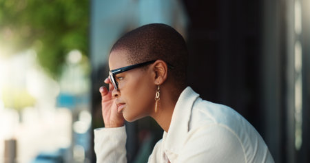 Business, African woman and thinking in office building or balcony for idea, planning or company. Female person, serious and vision as employee, realtor or professional for real estate agency in cityの写真素材