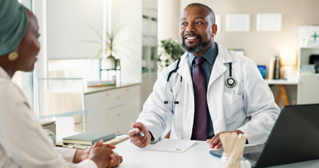 Discussion, healthcare and laptop with doctor and patient in office at hospital for consulting or feedback. Cpmputer, smile and medical professional man talking to person in clinic for checkupの写真素材