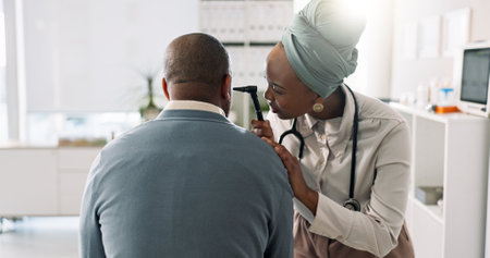 Doctor, medical check and ear with man, patient and test for tinnitus or hearing problem in clinic. Hospital, otoscope and back with healthcare, wellness and physician consultation for otolaryngologyの写真素材